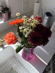 Autumn Floral Arrangement: A vibrant bouquet of orange and red roses in a purple vase, showcasing fall colors and seasonal decor.