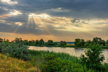 Beautiful landscape of summer picturesque nature with a river, vegetation on the banks, rays of...