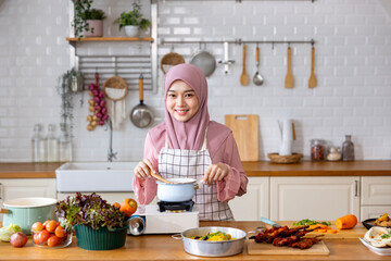 Happy Arab muslim housewife is preparing and cooking food in the kitchen for tasty halal meal at home in Middle east and Persian cuisine culture for Eid Mubarak feast after Ramadan