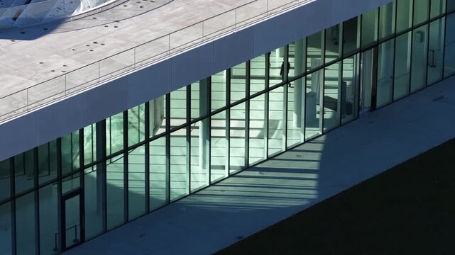 Aerial view of a sleek modern building with large glass panels casting clean shadows, showcasing minimalist architectural design and geometric lines.