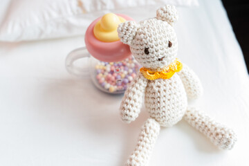 柔らかな朝の光に包まれた編みぐるみベアと哺乳瓶のおもちゃ