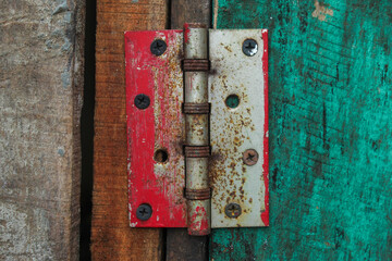 a rusty door hinge mounted between two wooden planks