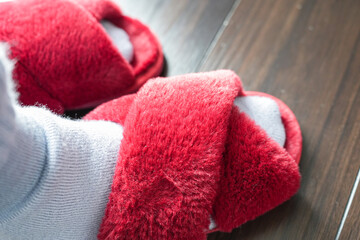 赤いもこもこスリッパを履いた足元