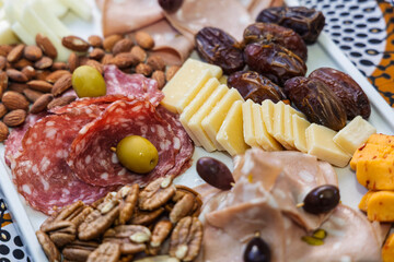 charcuterie board, platter with cheeses, fruits, and nuts, preserved cured meats, variety of salami, ham, walnuts,