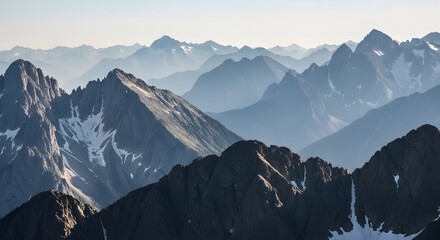 Layered Mountain Peaks with Snow Patches and Blue Hues Aerial View