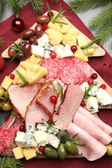 Delicious Christmas Charcuterie board with snacks, fir branches and bauble on grey table, flat lay