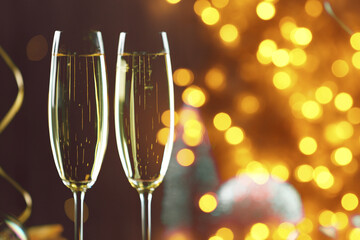 Sparkling wine in glasses, bokeh lights. New Year greeting card