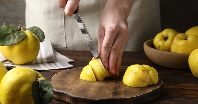 Woman cutting ripe quince at wooden table, closeup