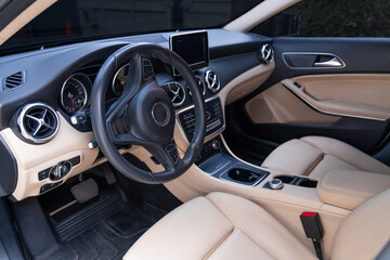 Photograph of the interior of a modern vehicle, empty, with leather seats and current design and technology.