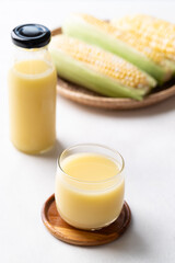 Sweetcorn milk in glass and bottle with fresh sweetcorn on white background, Alternative milk from plant, dairy free