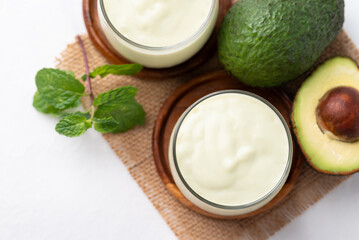 Avocado smoothie with milk in glass and avocado fruit on white background, Healthy drink, Top view