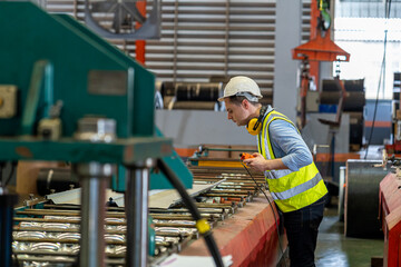 Factory workers are checking the operation of machines in a metal sheet factory.