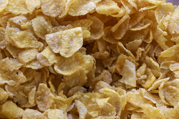 Close up of golden crunchy corn flake cereal for healthy breakfast. This textured food background offers delicious and sweet meal to start day with energy