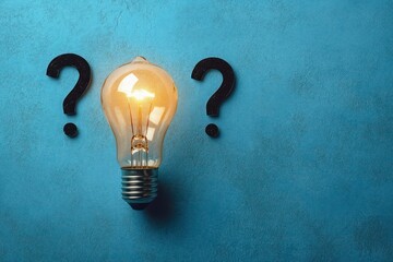 A glowing light bulb between two black question marks on a textured blue background symbolizing ideas and uncertainty