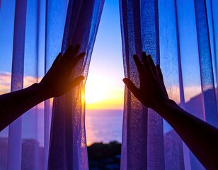 Two hands reaching out to pull sheer blue curtains open revealing a bright ocean sunset