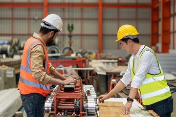 Workers in a metal sheet factory are working with machinery.