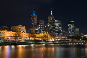 Yarra River, Melbourne CBD, Night cityscape view of the central business district skyline, with bridges and reflections on the calm water, people standing on a nearby waterfront platform