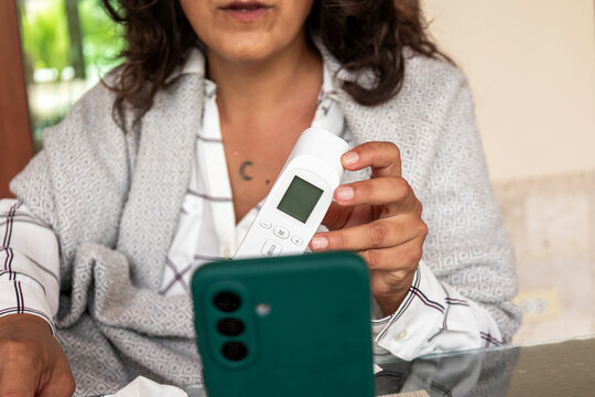 Woman measuring temperature during online medical consultation