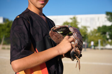 Young baseball player holding a glove, ready for practice or a game on the field