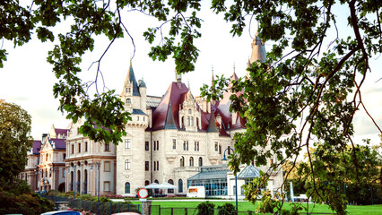 Realistic photo of a picturesque ancient fairy-tale castle on a green hill under a blue sky. Old...