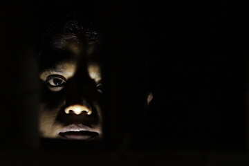 Artistic woman’s face lit in darkness, expressing resilience, life, and emotion through shadow and subtle human expression.