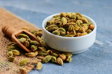 Green cardamom seeds in a bowl on a blue background