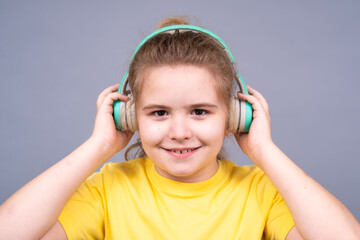 Kid listens to music. Child enjoys song. Kid smiles while wearing headphones. Child feels relaxed and happy with music. Kid enjoys sound. Cute teen listens to tunes. Teenager smiles with headphones.