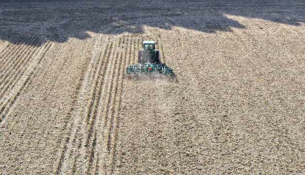Aerial view of tractor plowing soil. Tractor plowing farmland. Agricultural work. Tractor cultivating soil. Farming machinery. Tractor plowing land. Farm machinery working. Plowing from top.