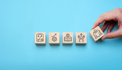 Change management process concept with hand arranging wooden blocks showing strategy, growth, learning, leadership, and teamwork icons, symbolizing organizational transformation, business improvement