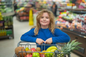 Children picking fresh fruits in the supermarket. Healthy vegetables in a kids shopping cart. Kid groceries at the market. Kid in a supermarket. Child shopping vegetables. Grocery shopping with kids.