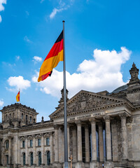 German flag waving above Reichstag. Symbol of unity and democracy. Blue sky and national pride. Landmark of Berlin. Reichstag Political symbol of Germany. German flag over Reichstag.
