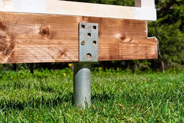 Close-up of a wooden deck post on green grass, highlighting the design and stability needed for outdoor living spaces. Ideal for construction techniques or home improvement projects.