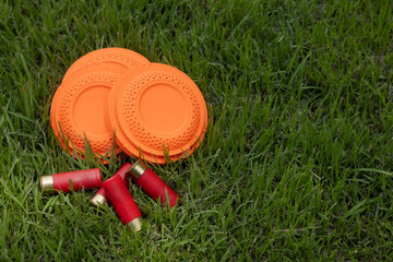 Clay shooting target and shotgun bullets on green background ,Clay Pigeon target game