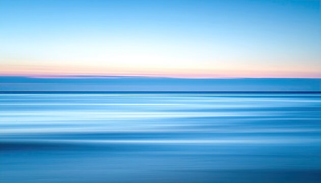 Blue ocean horizon with soft pink and orange sunset hues in the sky and tranquil water motion blur effect creating abstract serene seascape