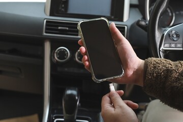 Hand holding smartphone and changing phone battery in car