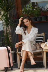 A beautiful woman sits on a wooden chair on the summer terrace of a cafe.