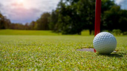 Golf ball is on a green lawn in a beautiful golf course with morning sunshine.