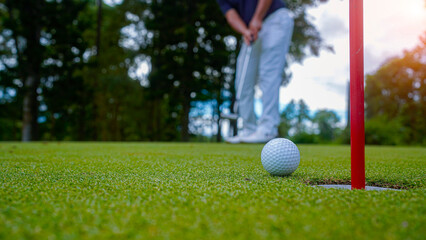 Golf ball is on a green lawn in a beautiful golf course with morning sunshine.