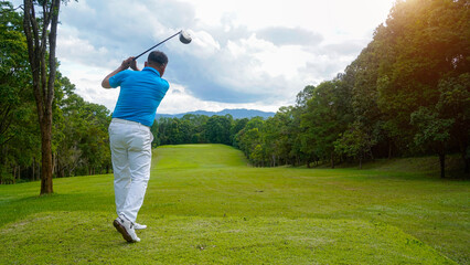 Golfer playing golf in the evening golf course, on sun set evening time.