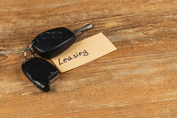 Keys on a wooden table with a note about leasing cars