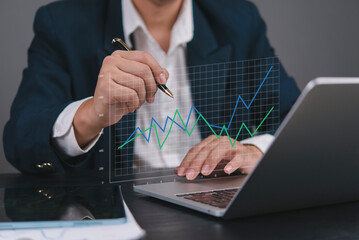 Businessman analyzing financial growth chart on laptop with data graph, planning investment and strategy for company success. Concept of financial analytics, economic growth, and business technology.