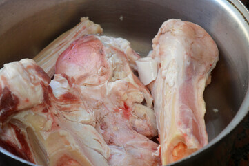 several pieces of raw beef bones in a pot, being prepared for making bone broth, bone marrow soup or stock, Bone broth is a nutrient-dense liquid made by simmering animal bones in water