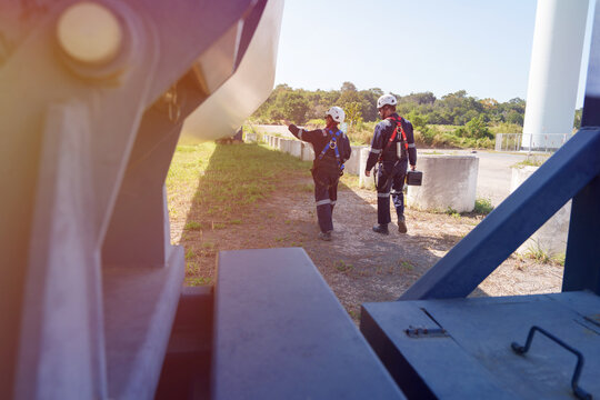 An engineer carefully examines a wind turbine blade at a construction site, placing a large blade on the ground to highlight the renewable energy technology.
