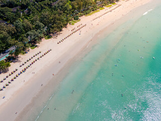 Aerial view of Kata beach with colorful beach umbrellas, tourist people relaxing on the sand,...