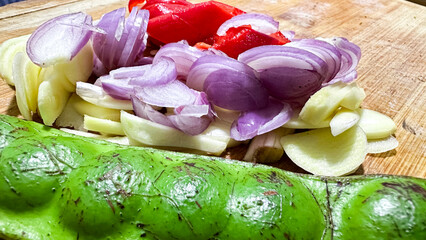 Fresh Petai with Red Chili, Shallots, and Garlic on Wooden Cutting Board for Traditional Asian Cooking Ingredients
