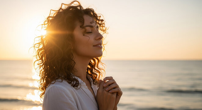 Serene woman meditating with closed eyes by the sea at golden hour