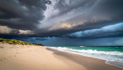 Dramatic seascape with a powerful storm front and ominous dark clouds looming over a tranquil turquoise ocean and sandy beach
