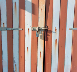 padlocked wooden door with white and red stripes