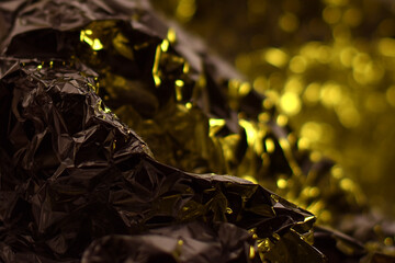 Yellow Metallic Foil Abstract Surface. Bright yellow metallic texture with reflective folds and shimmering light, creating an abstract luxury look.