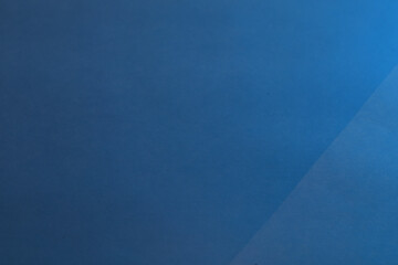 Blue Textured Paper with Diagonal Light Shadow. Minimal textured blue surface with diagonal lighting creating a calm geometric effect.